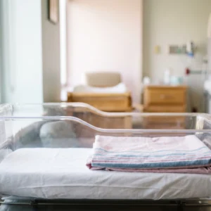Crib sheets in use: white knitted fitted crib sheet on a hospital bassinet mattress by International Linens