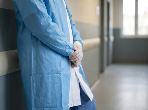 Lab coats and isolation gowns in use: white lab coat and blue reusable isolation gown by International Linens